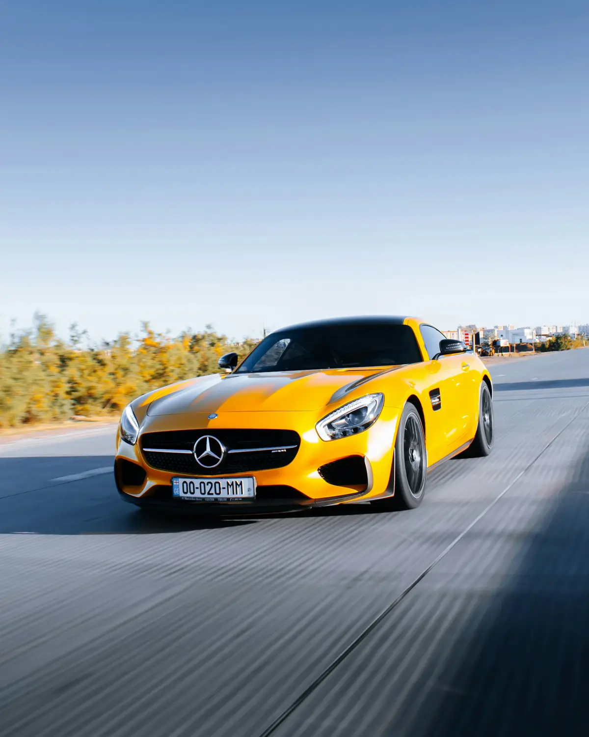 Yellow Mercedes-AMG GT rolling shot on an open road at dusk