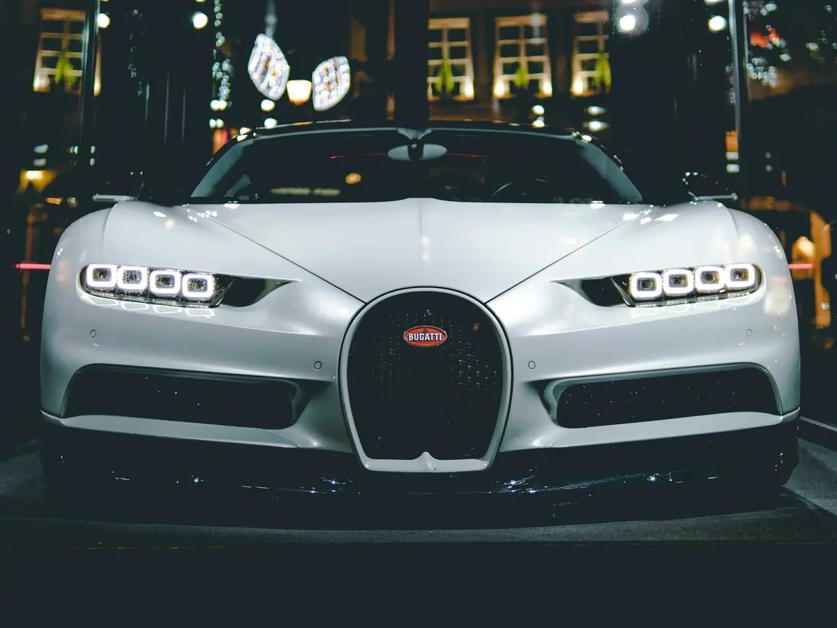 White Bugatti Chiron head-on at night, city lights behind