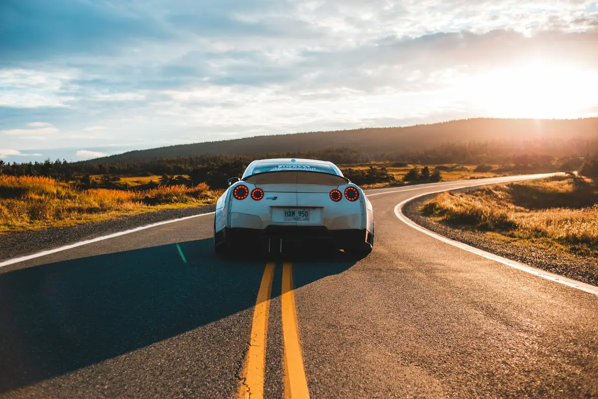 Silver Nissan GT-R from behind on a winding rural highway at golden hour