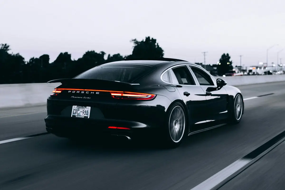 Black Porsche Panamera Turbo on the highway at dusk, rear three-quarter rolling shot